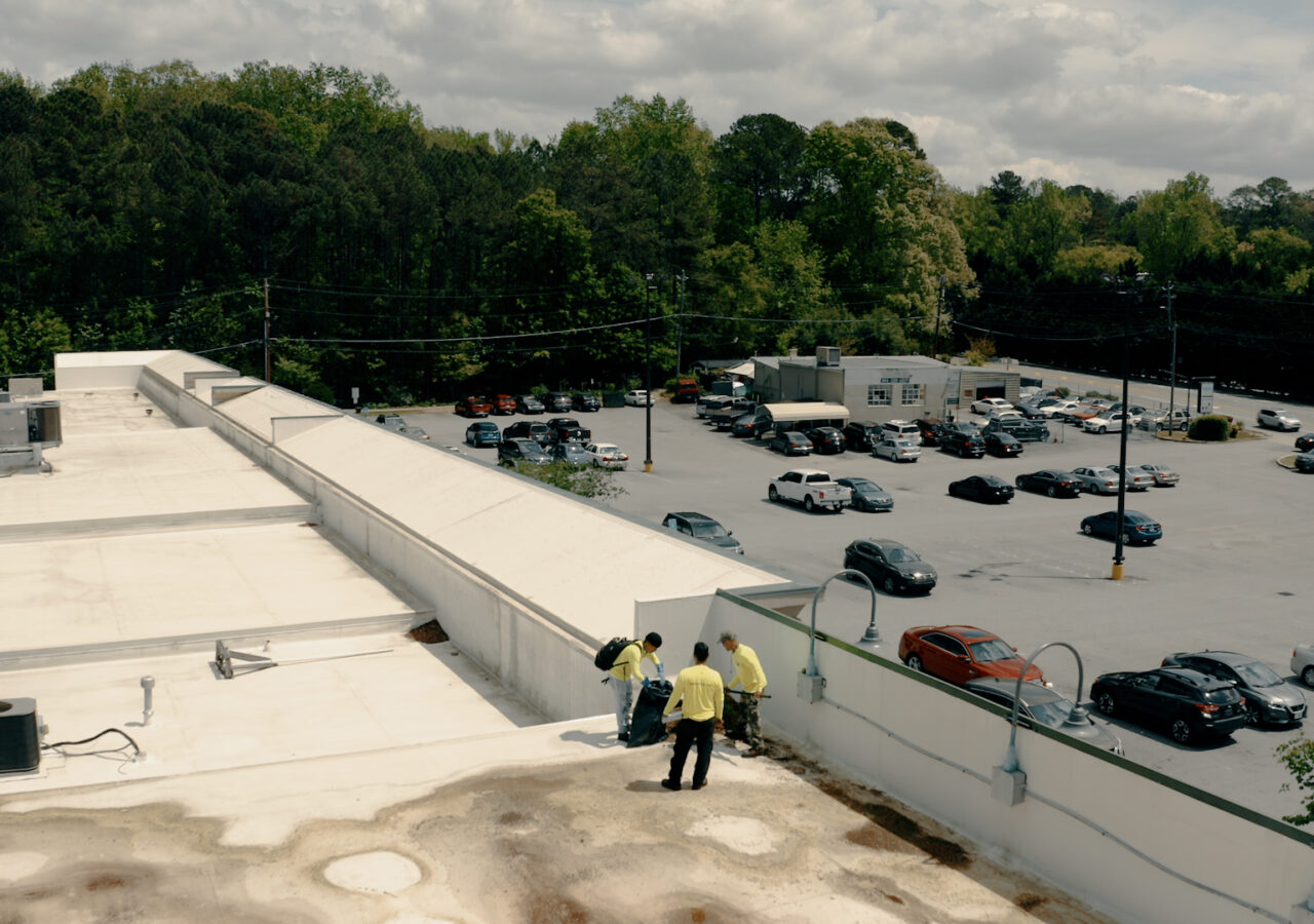 roofers on a tall building doing an inspection, looking out over a parking lot